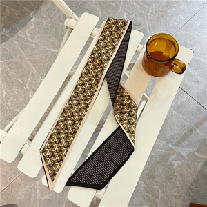 Dettaglio di un foulard in seta con stampa geometrica su una sedia bianca