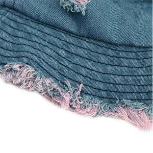 Close-up of blue denim bucket hat featuring pink fringe edges and reinforced stitching