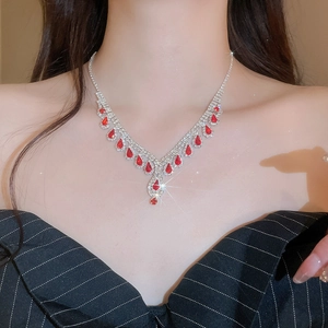 Detail of silver V-shaped necklace with red teardrop gem and shimmering crystal fringe