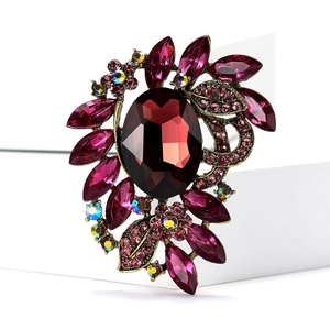 Macro detail of luxury alloy brooch with red oval gemstone and purple floral rhinestones
