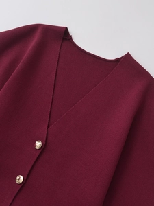 Detailed macro view of the V-neckline and gold buttons on a burgundy knit cardigan