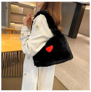 Detail of soft black plush shoulder bag with a vibrant red heart patch decoration