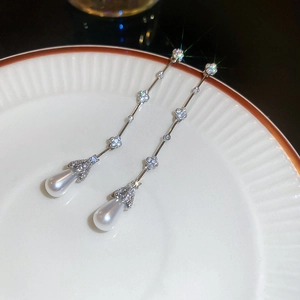 Macro shot of silver tassel earrings with zircon flowers and waterdrop pearl pendants
