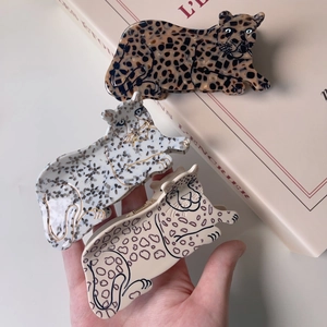 Detailed close-up of leopard-shaped acetate hair claws in dark, white, and beige patterns