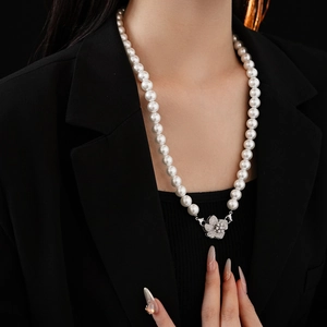 Detailed view of women's white faux pearl necklace with zircon flower clasp on model