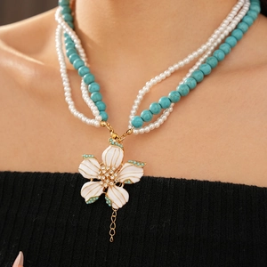 Détail d'un collier de perles multicouche avec turquoise, perles et pendentif fleur