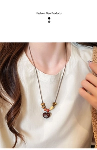 Detail of vintage wooden beaded long necklace with heart pendant and metallic saturn logo