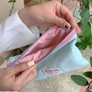 Interior view of mint green nylon cosmetic bag with pink lining and brand label