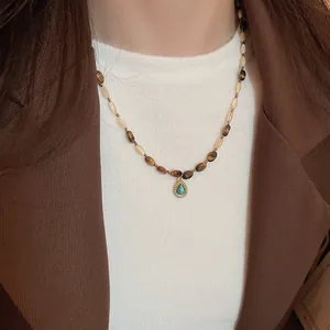 Detail of beaded tiger eye necklace with turquoise teardrop pendant on a model