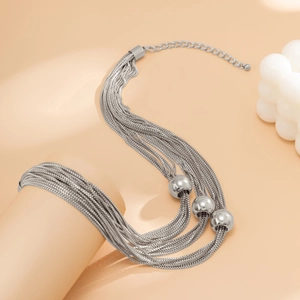 Detail of silver multilayer chain necklace featuring three polished metal round beads