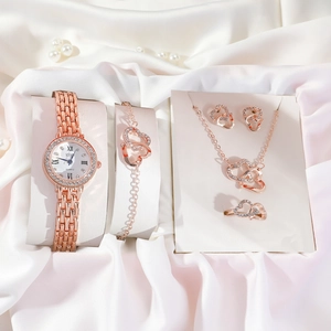Close-up of 5-piece rose gold jewelry set with heart motifs on white silk background