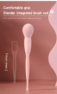 Detail of pink makeup brush with slender waist-shaped ergonomic handle and fluffy bristles