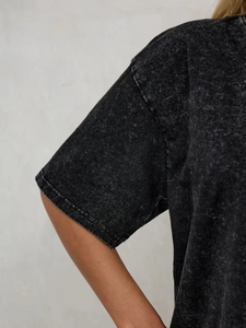 Detail of washed black vintage T-shirt showing heavy cotton texture and dropped shoulder seam