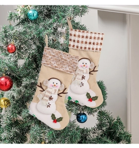 Christmas stockings with snowman decor hanging on a decorated tree near a fireplace