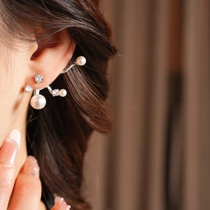 Nahaufnahme eines eleganten silbernen Ohrrings mit eingelegten Perlen und Zirkonia-Steinen