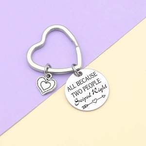 Custom engraved stainless steel heart keychain with rhinestone charm on a purple background