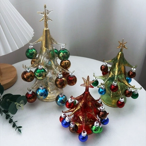 Three-piece set of red, green and gold glass Christmas tree ornaments on white table