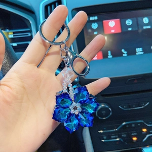 Close-up of blue crystal snowflake keychain with silver ring held in car interior