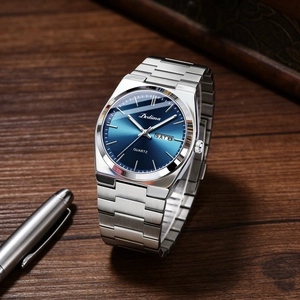 Close-up of elegant men's steel watch with blue dial on wooden desk with luxury pen