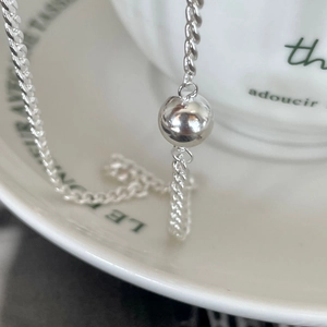 Minimalist 925 sterling silver bead chain necklace draped over a white ceramic tea cup