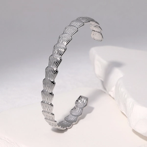 Detail showing the overlapping feather texture on a silver stainless steel open bangle