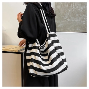 Model wearing a large black and white striped canvas tote bag over the shoulder