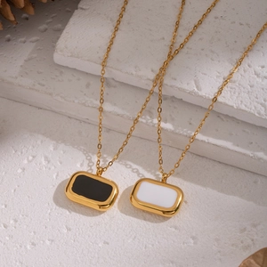 Détail de pendentifs rectangulaires en émail noir et blanc sur chaînes en acier doré