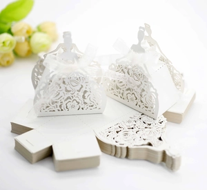 Macro detail of laser-cut white wedding candy boxes with intricate floral lace and silhouettes