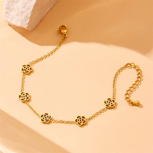 Elegant gold titanium steel bracelet featuring hollow camellia charms on a warm beige background