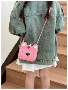 Pink bear-shaped kids crossbody bag with strawberry detail shown on a child model