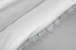 Nahaufnahme der weichen weißen Stoffstruktur mit elegantem Kunstpelzbesatz an den Rändern