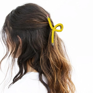 Detailed view of creative yellow pencil hair claw clip worn on wavy hair in a back view