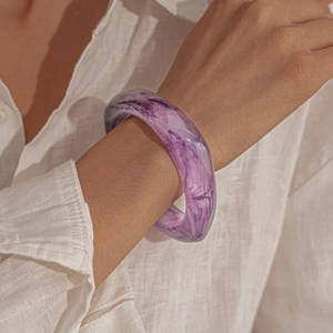 Detail of purple marble resin bangle with translucent swirl texture on model wrist