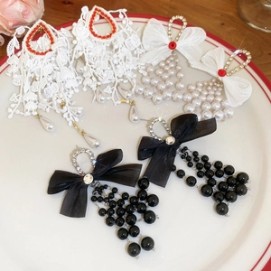 Detailed shot of bow earrings with tassels and pearls in a ceramic tray