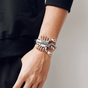 Close-up of a masculine silver scorpion-shaped cuff bracelet on a male model wrist