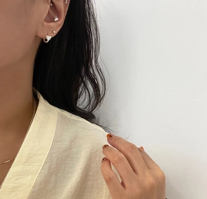 Detail of 925 sterling silver bow and heart stud earrings worn on model's ear