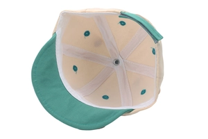 Detailed interior of a beige baby baseball cap showing seams and green embroidery