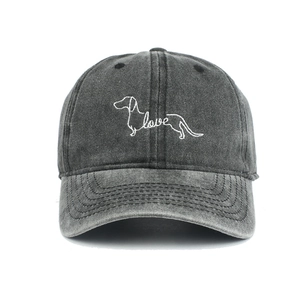 Close-up of a dachshund puppy and love embroidery on a dark grey washed cotton baseball cap