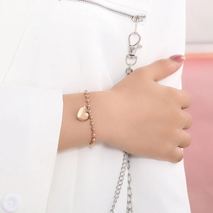 Gros plan du bracelet à perles en or rose avec pendentif cœur sur un poignet