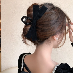 Detail of elegant black velvet bow hair claw clip styled on a low bun hairstyle