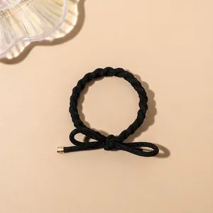 Detail of high-elastic black braided hair tie with elegant bow and gold metal tips