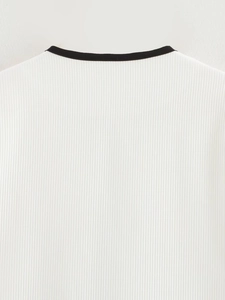 Detailed close-up of white ribbed knit fabric with black crew neck trim on casual top