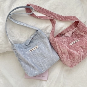Détail de sacs fourre-tout en velours bleu et rose avec cœurs embossés et étiquette de marque