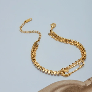 Close-up of gold double-layer bracelet with safety pin pendant and zircon stones