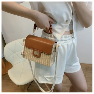 Macro detail of the woven straw box bag with brown pleated handle and gold clasp lock