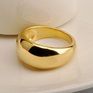 Detailed view of a wide dome gold ring with a high-polished metallic surface finish