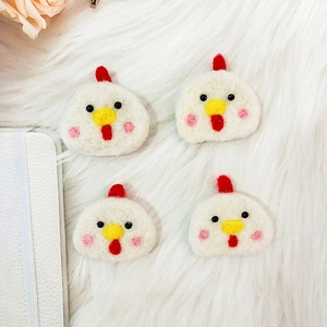 Detailed view of four handmade wool felt chick pendants on a soft white plush background