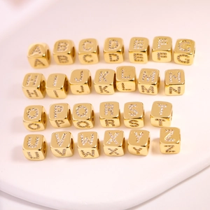 Macro shot of 26 gold letter beads with micro-paved white zircons for DIY jewelry making
