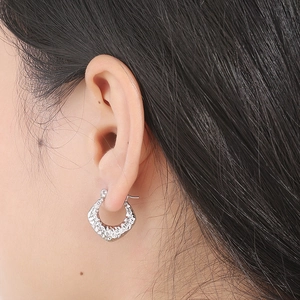 Close-up of a silver hammered texture C-shaped earring worn with minimalist style
