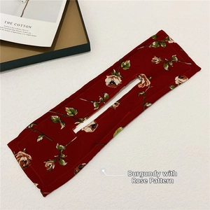 Detail view of burgundy rose print fabric hair bun maker on a white textured background